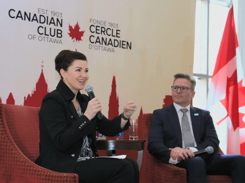 A speaker addresses the room in front of the Club’s red Parliament-skyline backdrop