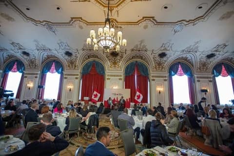 A ballroom luncheon with Canadian flags beside the stage